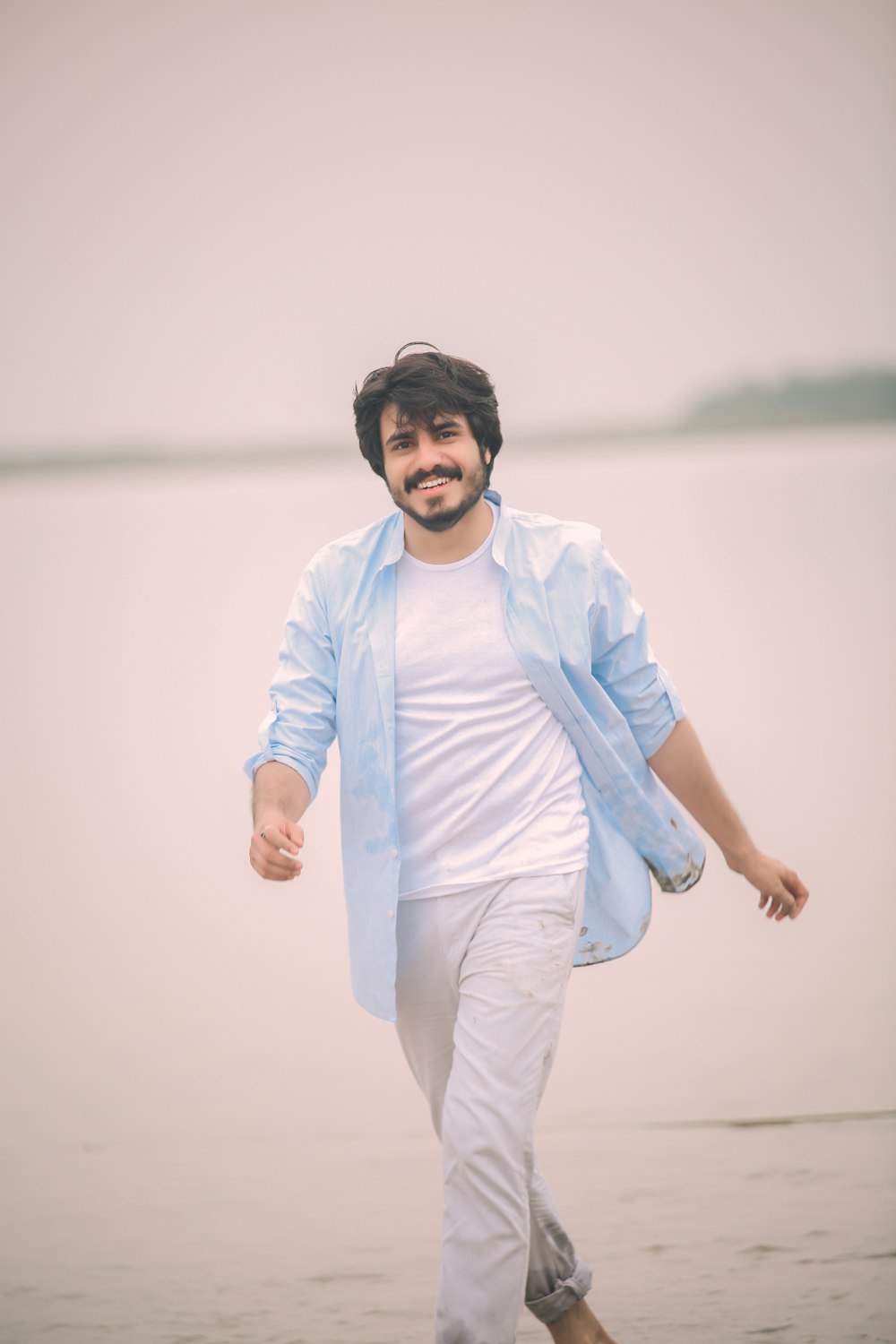 woman in white long sleeve shirt and white pants standing on water