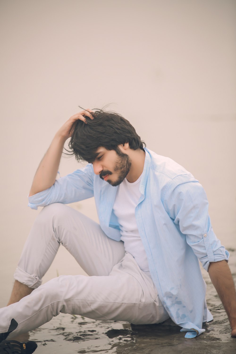 a man sitting on the ground with his hand on his head