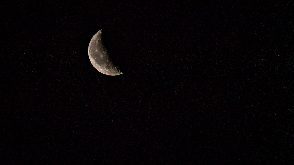 a half moon is seen in the dark sky