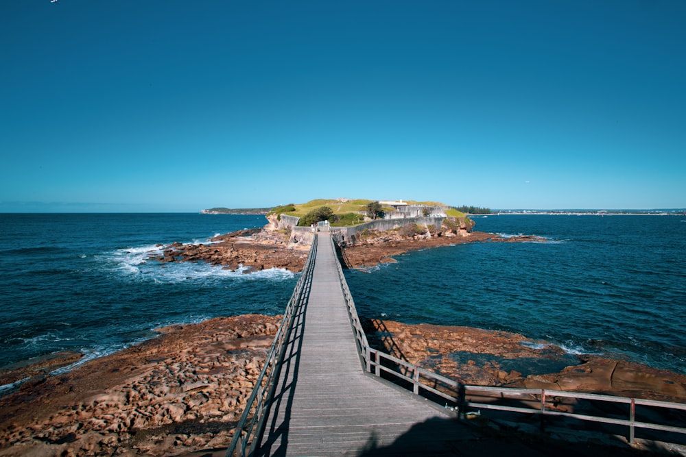 brown wooden bridge on blue sea under blue sky during daytime