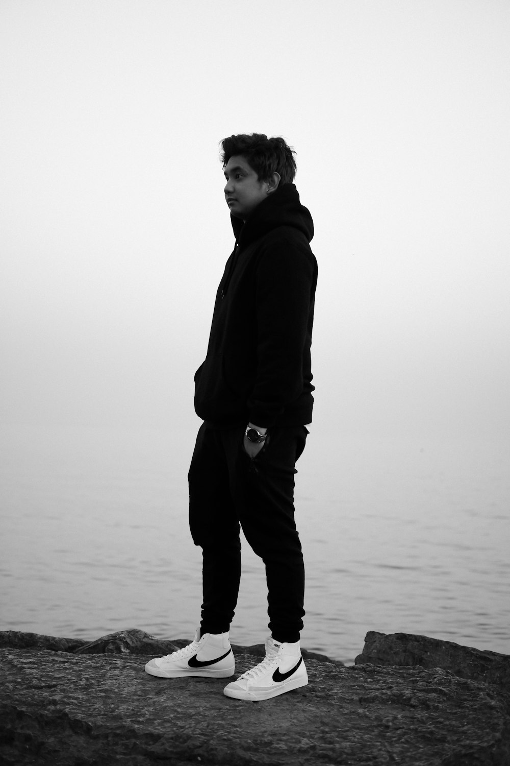 Hombre con chaqueta negra de pie en la playa