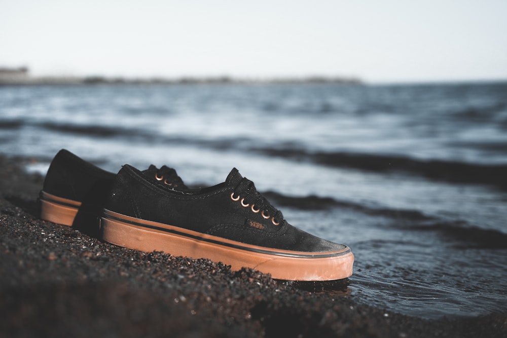 black and brown lace up shoes on brown sand near body of water during daytime