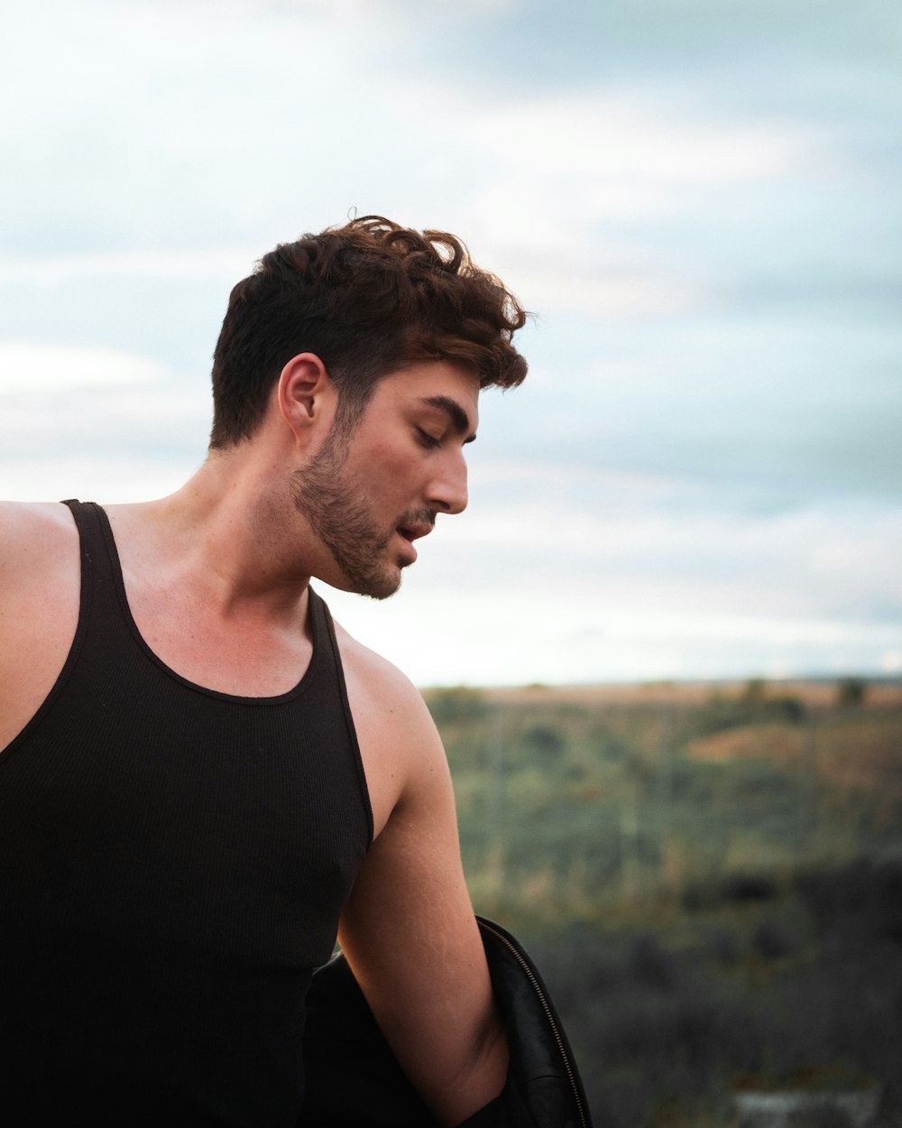 man in black tank top standing on green grass field during daytime