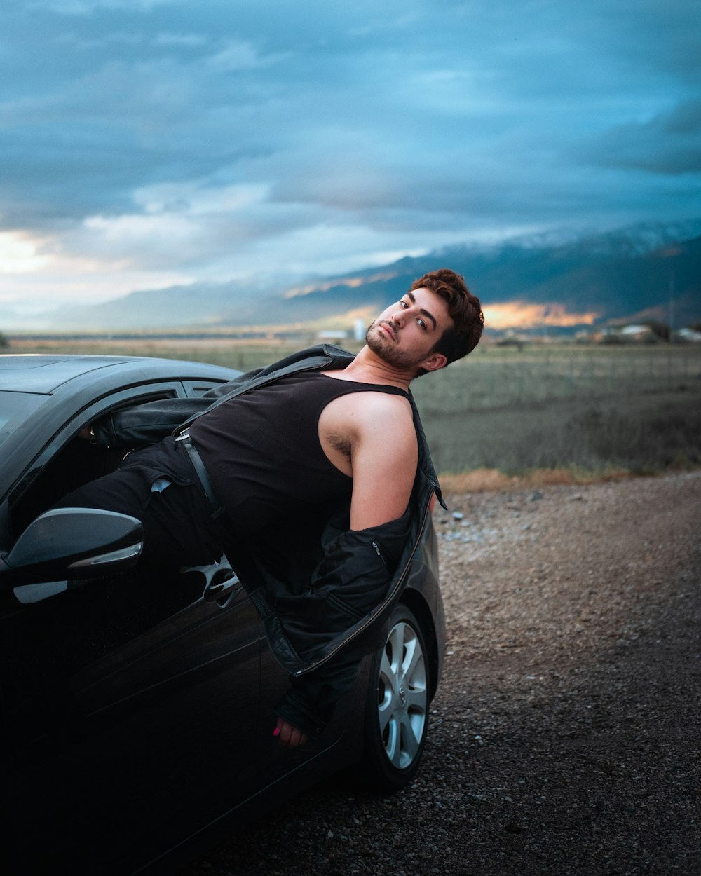 woman in black tank top standing beside black car during daytime