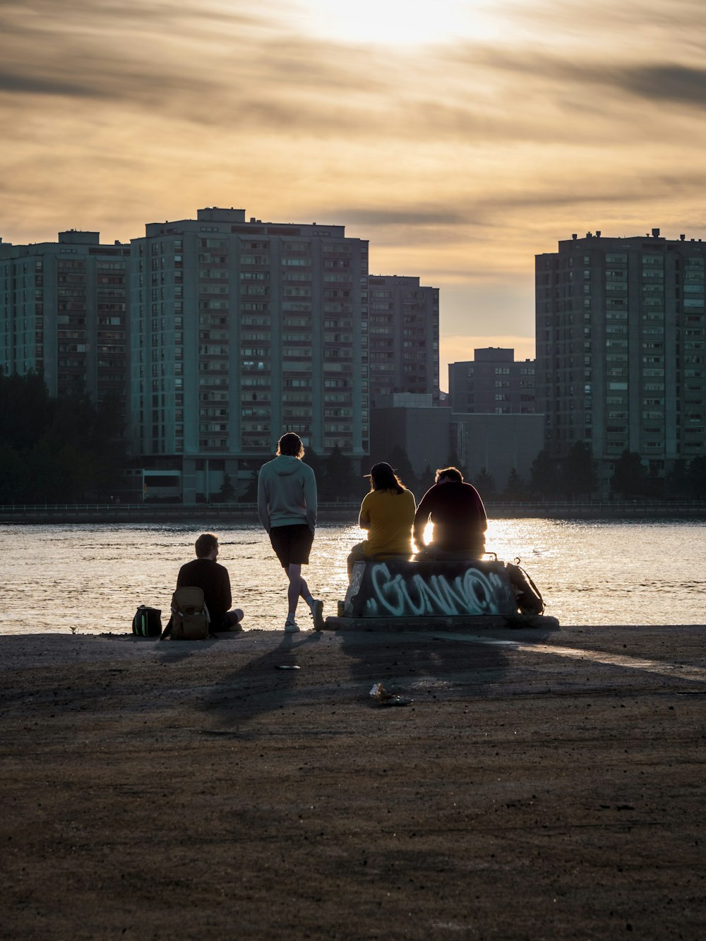 2 Männer sitzen während des Sonnenuntergangs am Strandufer