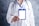 A person wearing a white lab coat is holding a blank ID badge with a blue lanyard. A stethoscope is draped around the neck, suggesting a medical professional. The background is a textured gray.