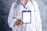 A person wearing a white lab coat is holding a blank ID badge with a blue lanyard. A stethoscope is draped around the neck, suggesting a medical professional. The background is a textured gray.