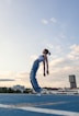 man in white tank top and blue denim jeans jumping on mid air during daytime