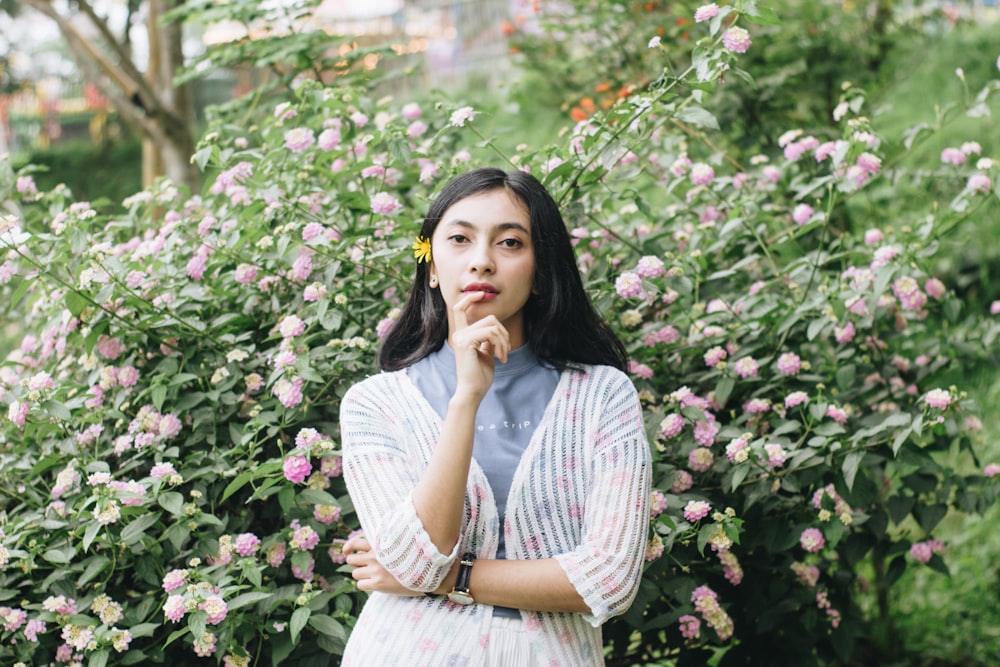 woman in white and gray striped dress standing beside pink flowers