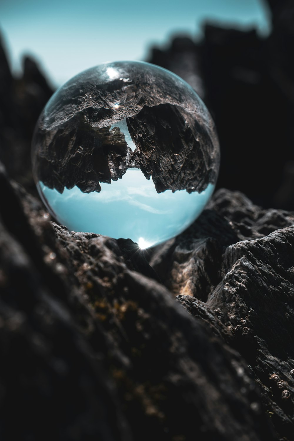 clear glass ball on black and gray rock