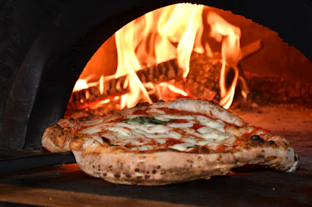 Pizza assando em forno a lenha