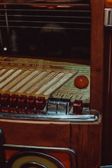 A vintage jukebox with intricate details, featuring a selection panel with various buttons and song slots. The surface is wooden with metallic and glass elements, giving it a classic, retro appearance.
