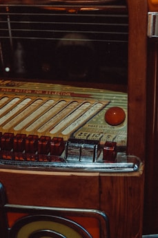 A vintage jukebox with intricate details, featuring a selection panel with various buttons and song slots. The surface is wooden with metallic and glass elements, giving it a classic, retro appearance.