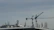 Cranes towering over a building rooftop with various antennas and equipment, set against a cloudy sky.