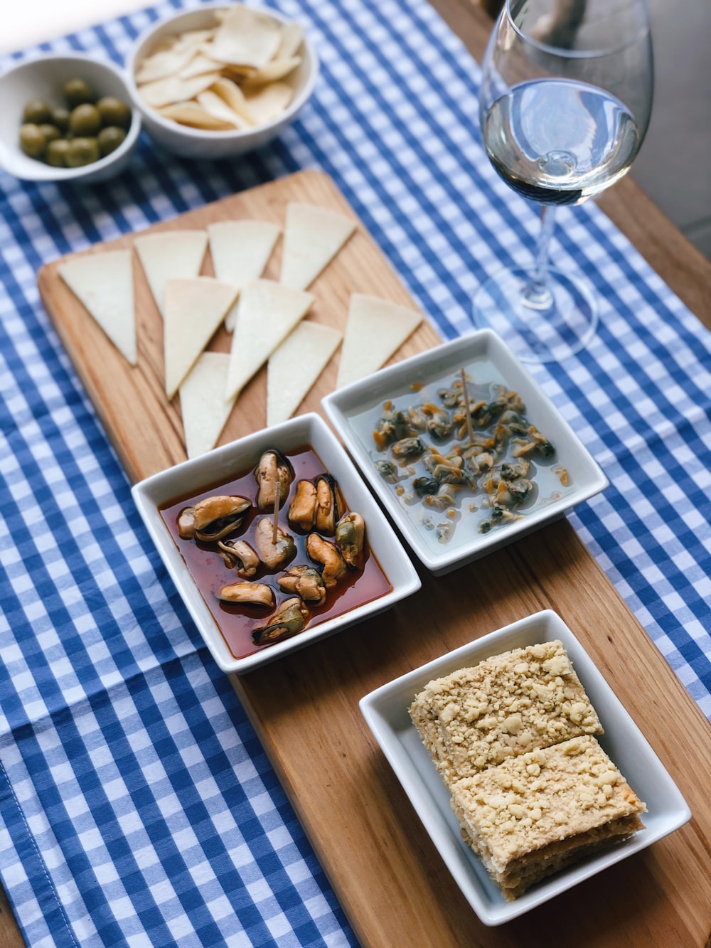 青と白の市松模様のテーブルクロスに食べ物が入った白いセラミックボウル