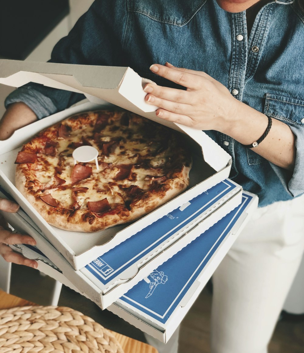 Persona sosteniendo pizza en la caja