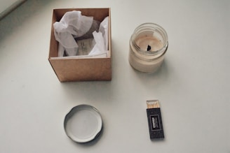 A stylish box open to reveal self-care items like candles and bath salts, set on a minimalist white background.