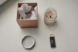 Minimalist arrangement of Sylvan’s aroma pouches and candles on a soft grey surface with natural light.