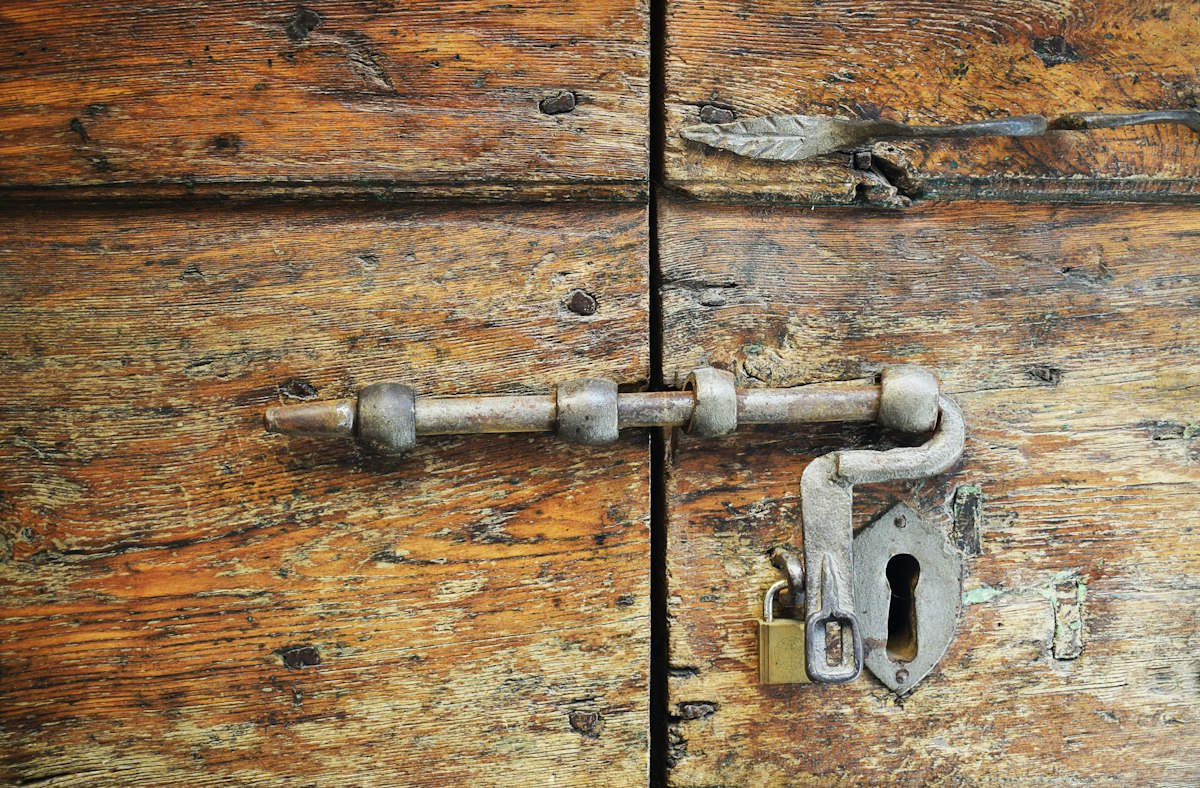 close-up of hands repairing a door hinge with a screwdriver