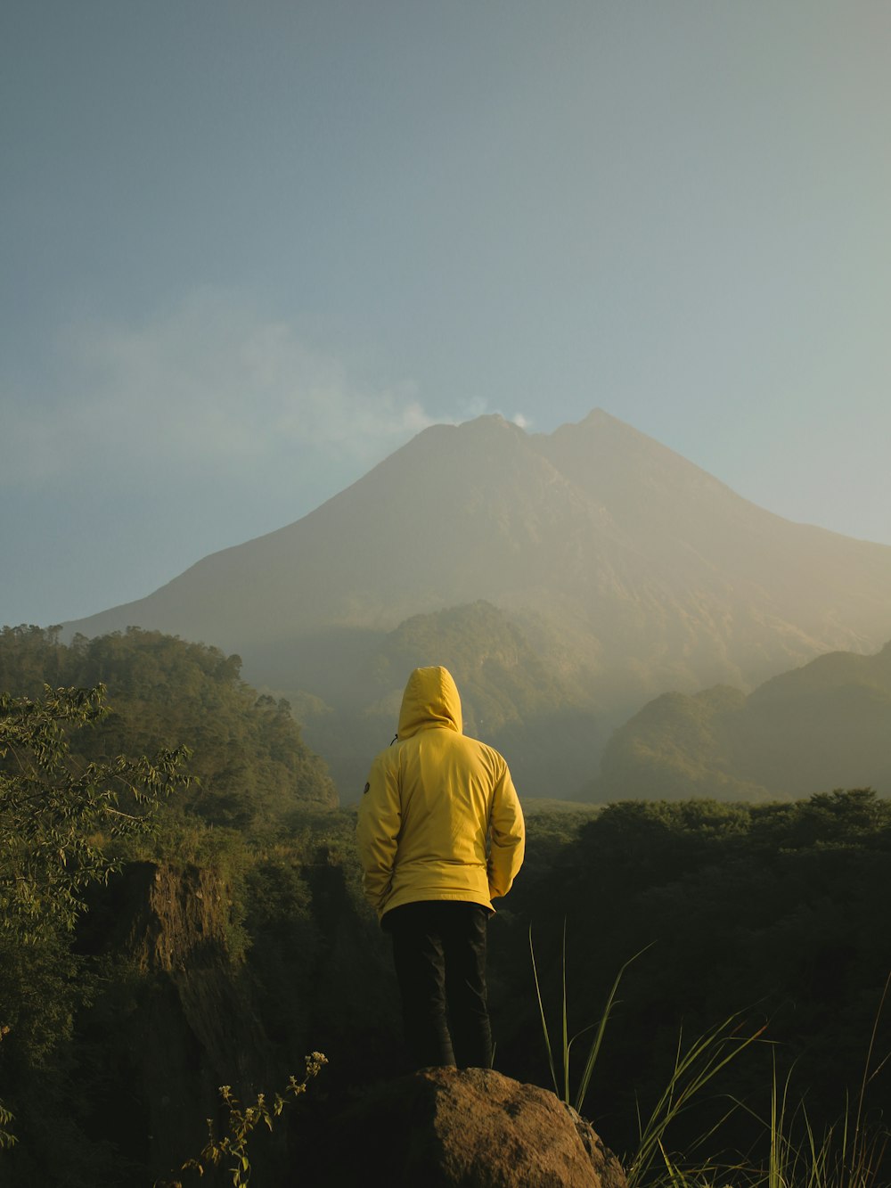 person in yellow hoodie standing on green grass field during daytime