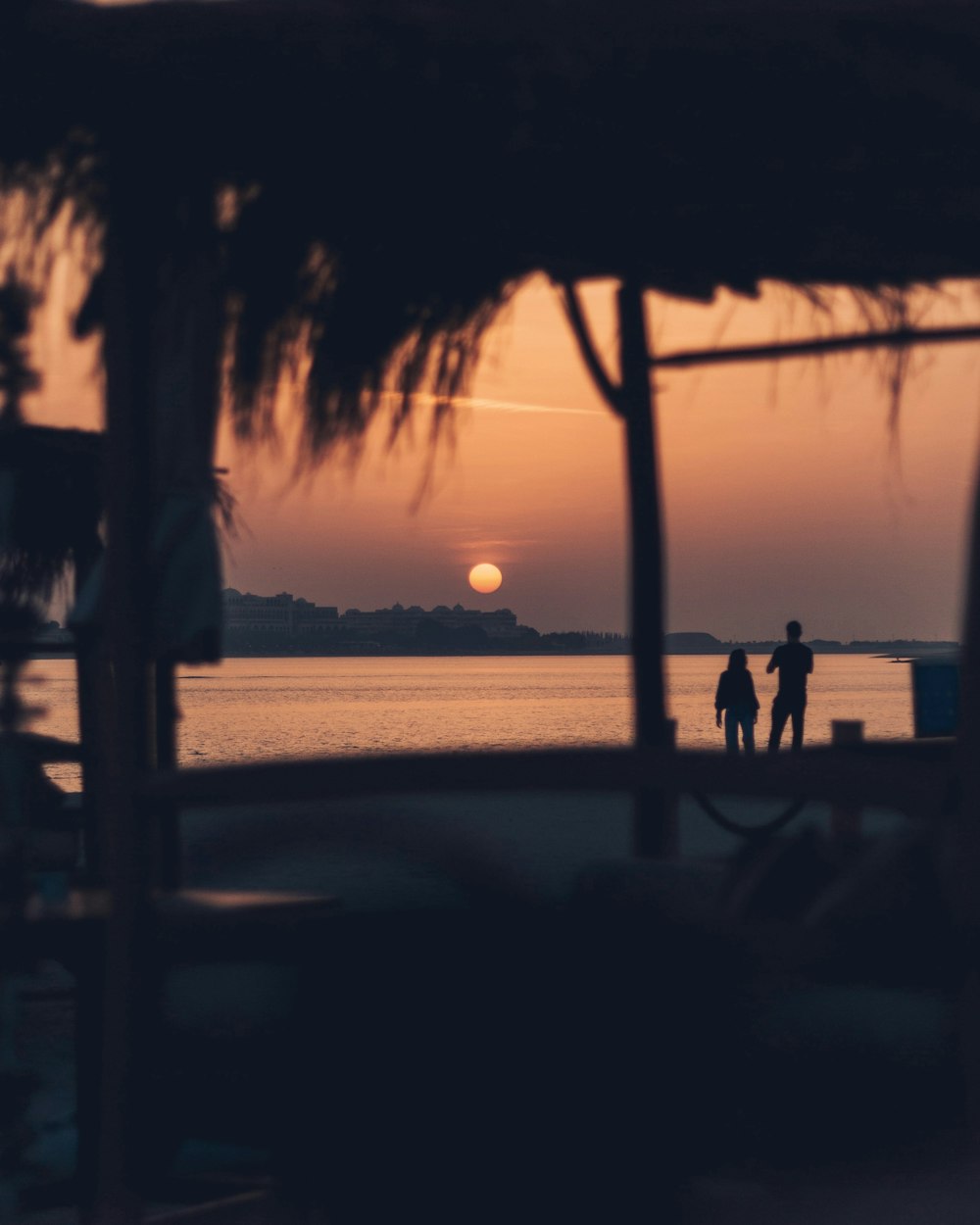 silhouette of people standing on beach during sunset