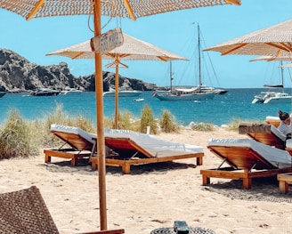 brown wooden beach lounge chairs on beach during daytime