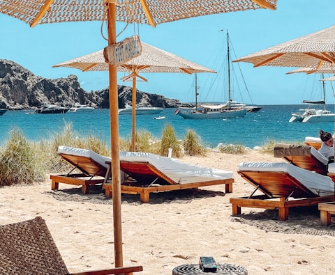 brown wooden beach lounge chairs on beach during daytime