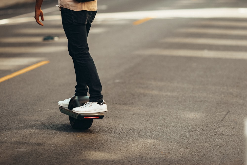 person in black pants and black and white sneakers walking on gray asphalt road during daytime