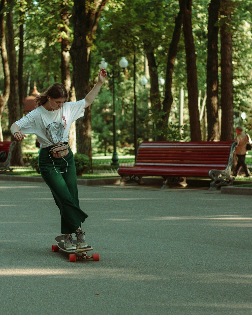 man in white shirt and green pants riding red kick scooter on road during daytime