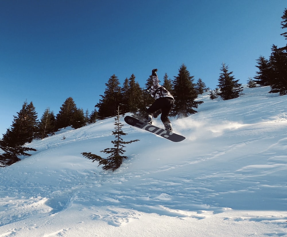 person in black jacket and black pants riding ski blades on snow covered ground during daytime