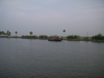 A serene view of Kerala’s backwaters at sunset with a traditional boat floating gently.