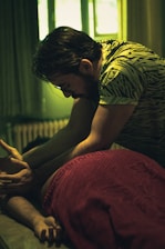 man in brown and white stripe shirt sitting on bed