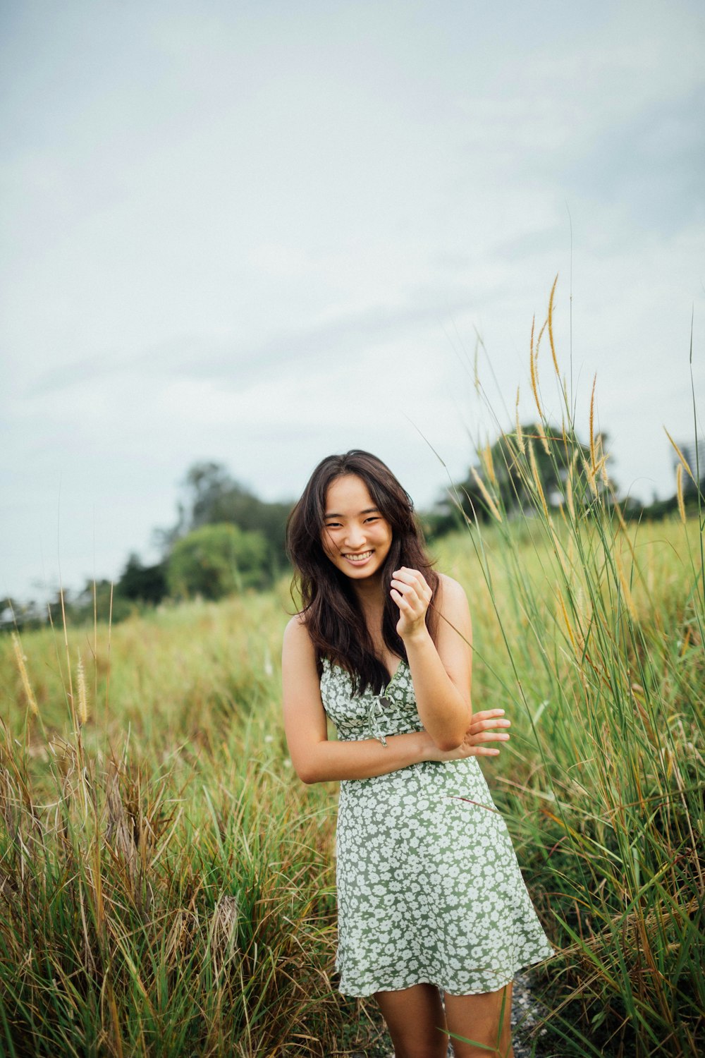 woman in black and white floral sleeveless dress standing on green grass field during daytime