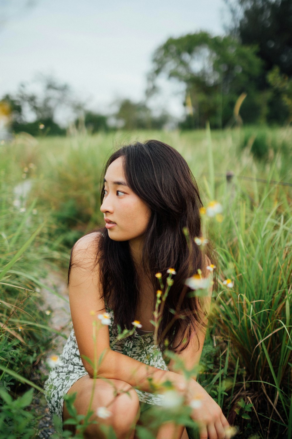 woman in white sleeveless dress standing on green grass field during daytime