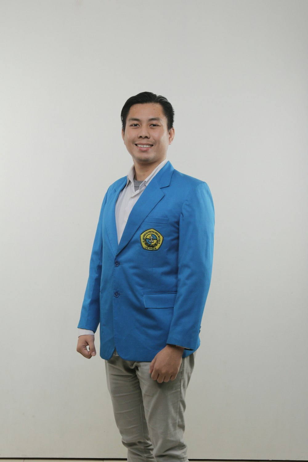 a man in a blue jacket standing in front of a white wall