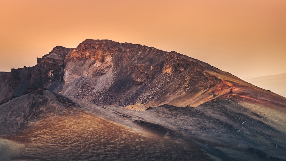 brown and white mountain beside body of water during daytime