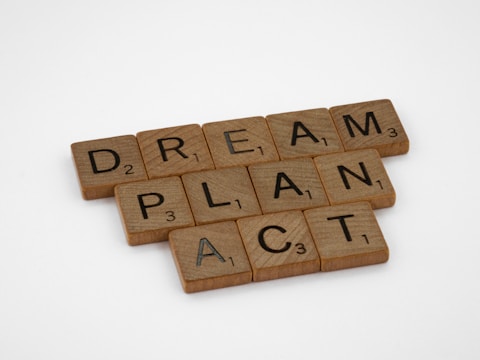 brown Scrabble pieces that spell out Dream, Plan and Act