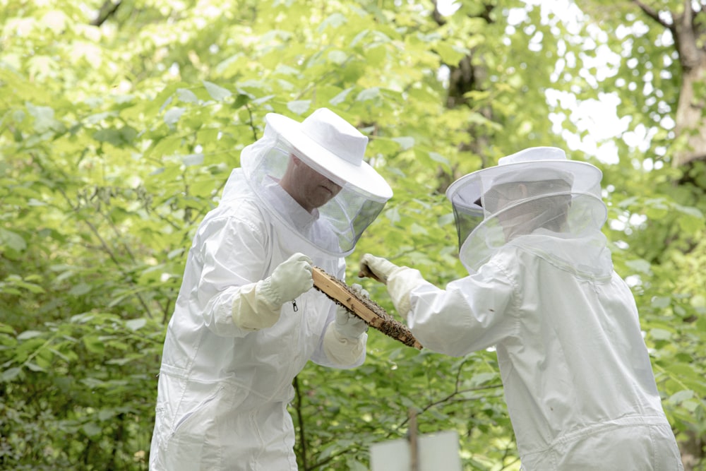 Uomo in camicia bianca a maniche lunghe e cappello bianco in piedi sul tronco di legno marrone durante il giorno