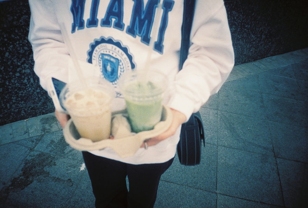 person in white and blue pullover hoodie holding white plastic cup