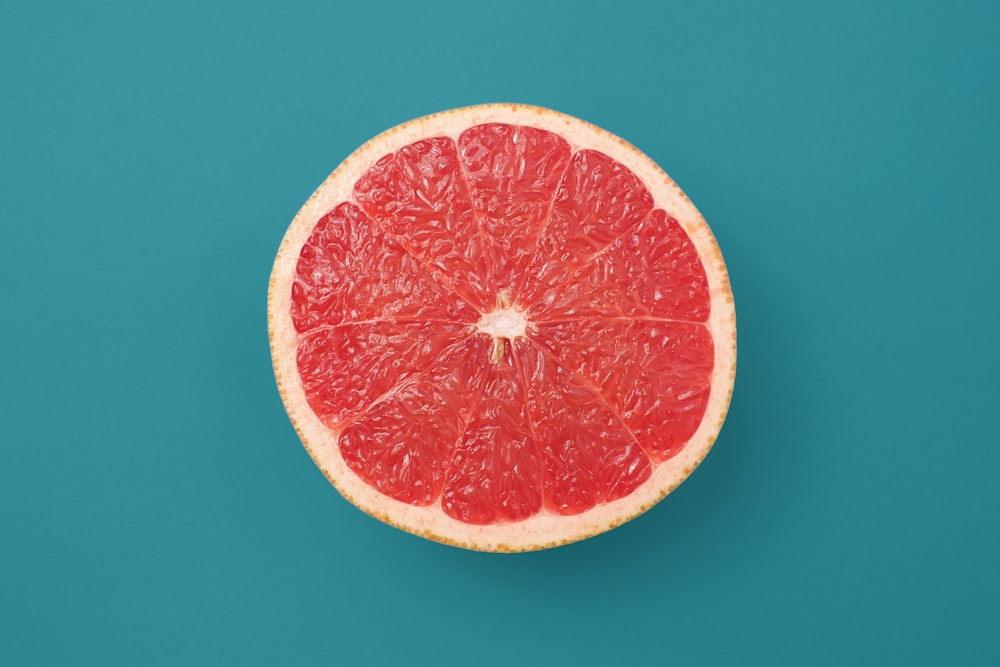 青の背景にスライスしたオレンジ色の果物