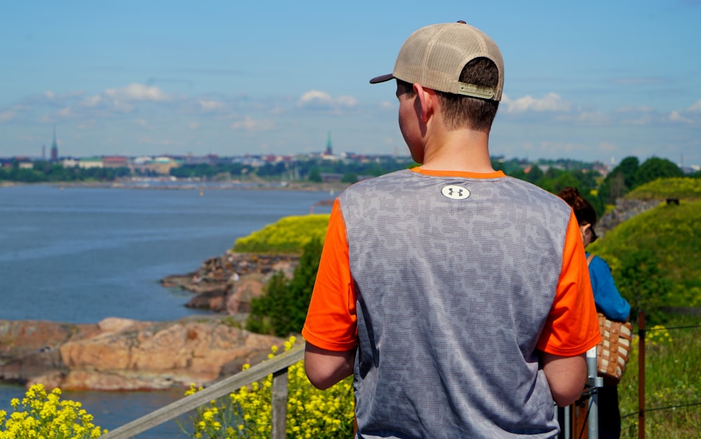 man in grey and orange crew neck t-shirt standing on the bridge