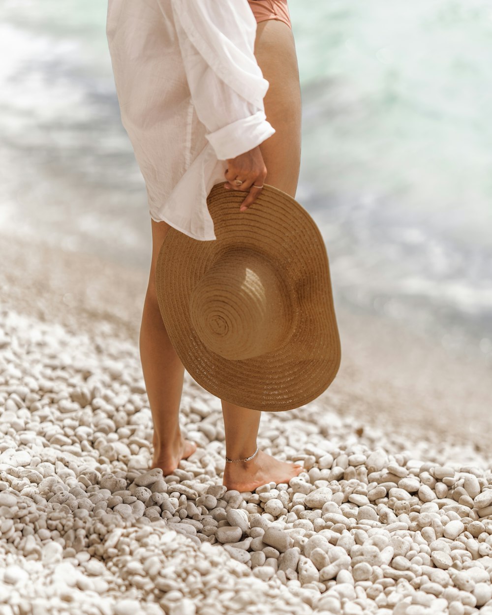 Frau in weißem Kleid tagsüber am Strand spazieren