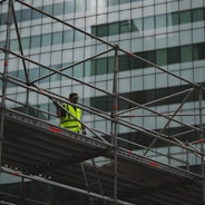 man in yellow jacket and black pants standing on black metal staircase