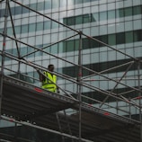 man in yellow jacket and black pants standing on black metal staircase