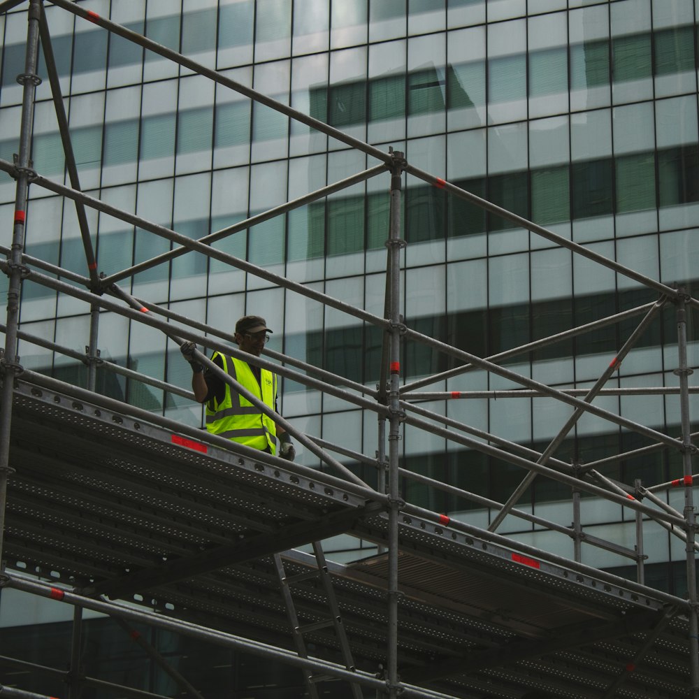 man in yellow jacket and black pants standing on black metal staircase