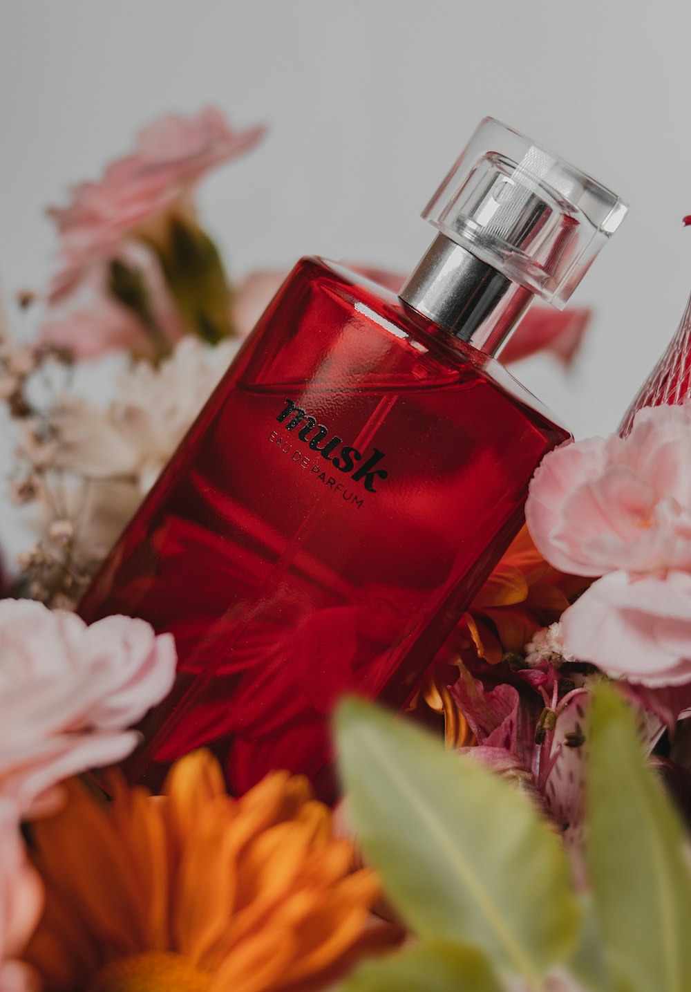pink perfume bottle beside pink roses