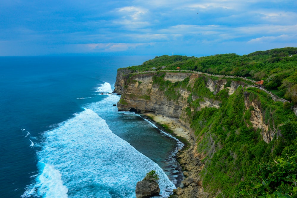 green and brown mountain beside blue sea under blue sky during daytime