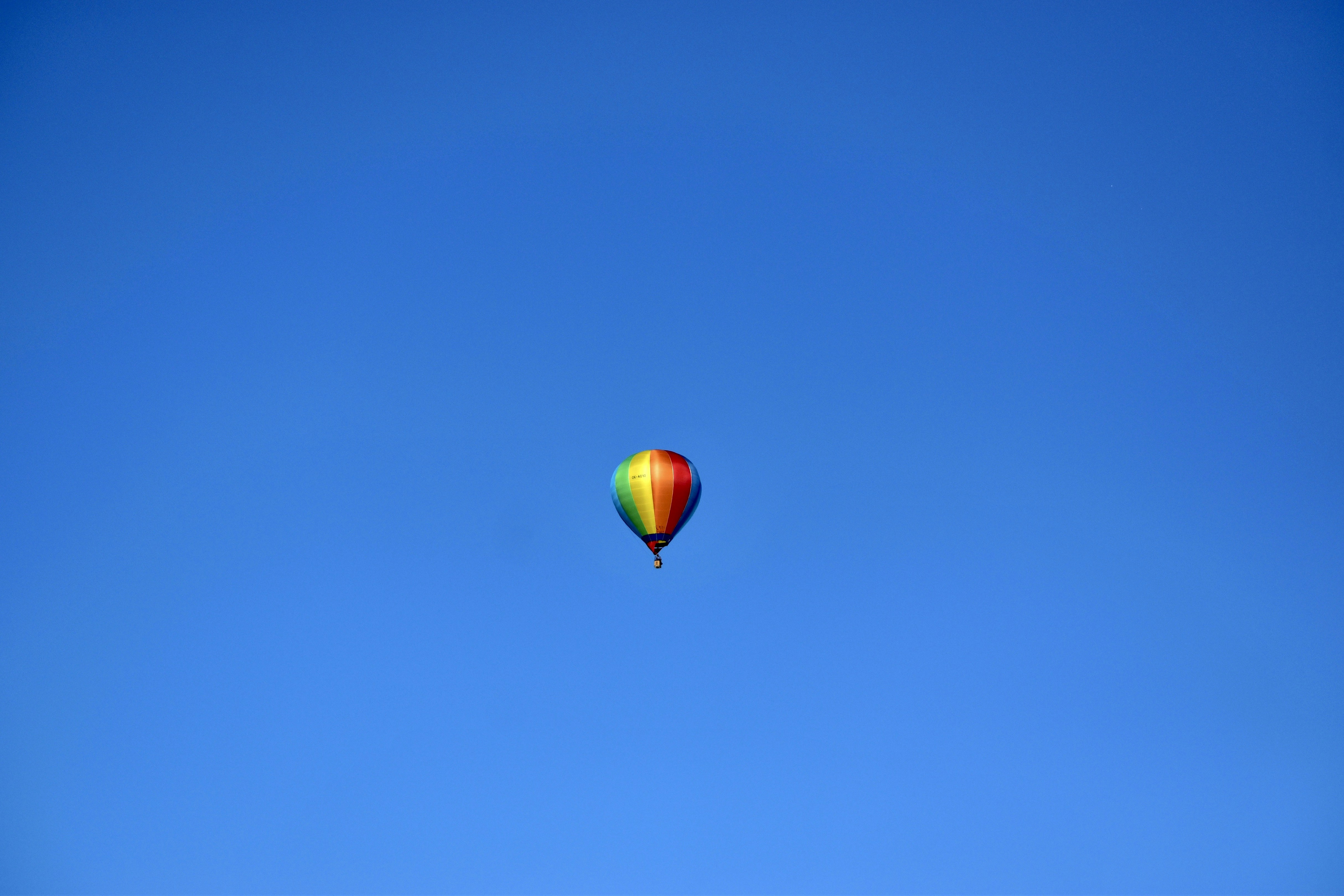 Rainbow coloured hot air balloon in a blue sky