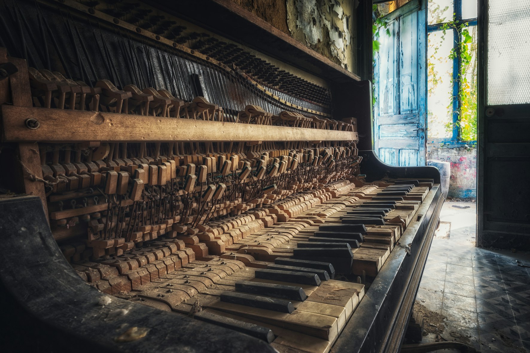 Creepy looking old broken piano with hammers and strings exposed.
