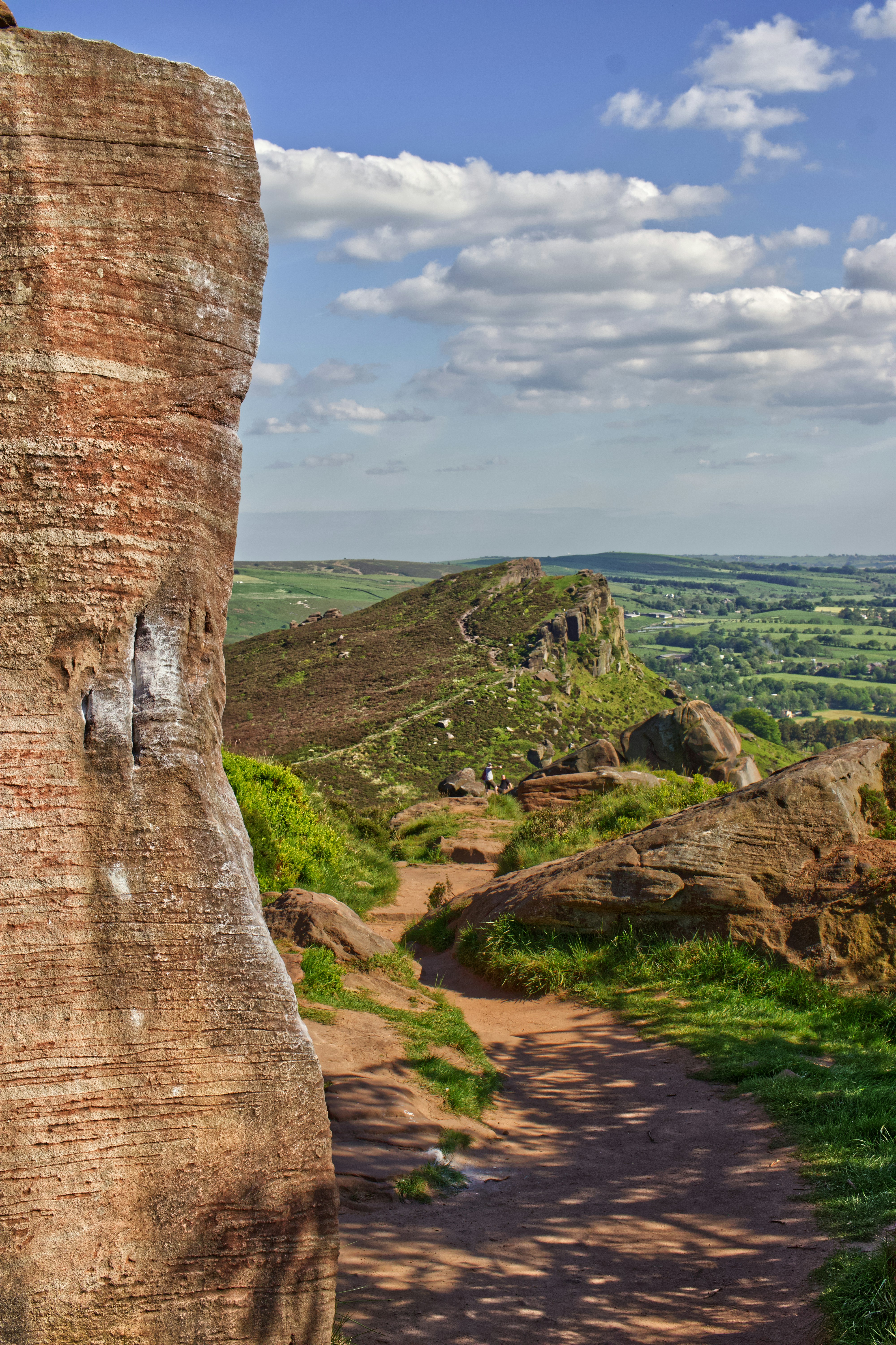 Edificio de hormigón marrón en campo de hierba verde bajo nubes blancas durante el día